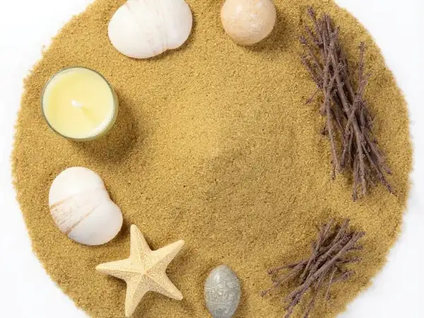 Centro de mesa marino con arena mostaza, conchas y vela